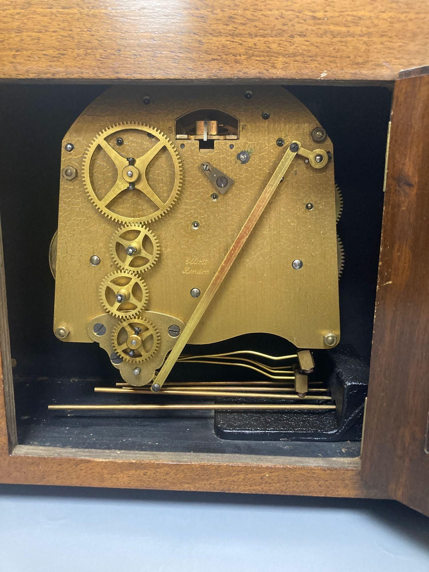 A mahogany mantel clock with ebonised decoration, by Elliott of London, width 33cm, height 25cm